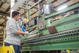 Woman using a large assembly line machine.
