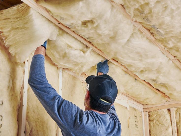 A man installs insulation into a building