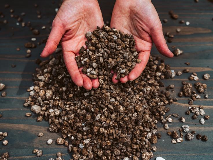 two hands holding asphalt pellets