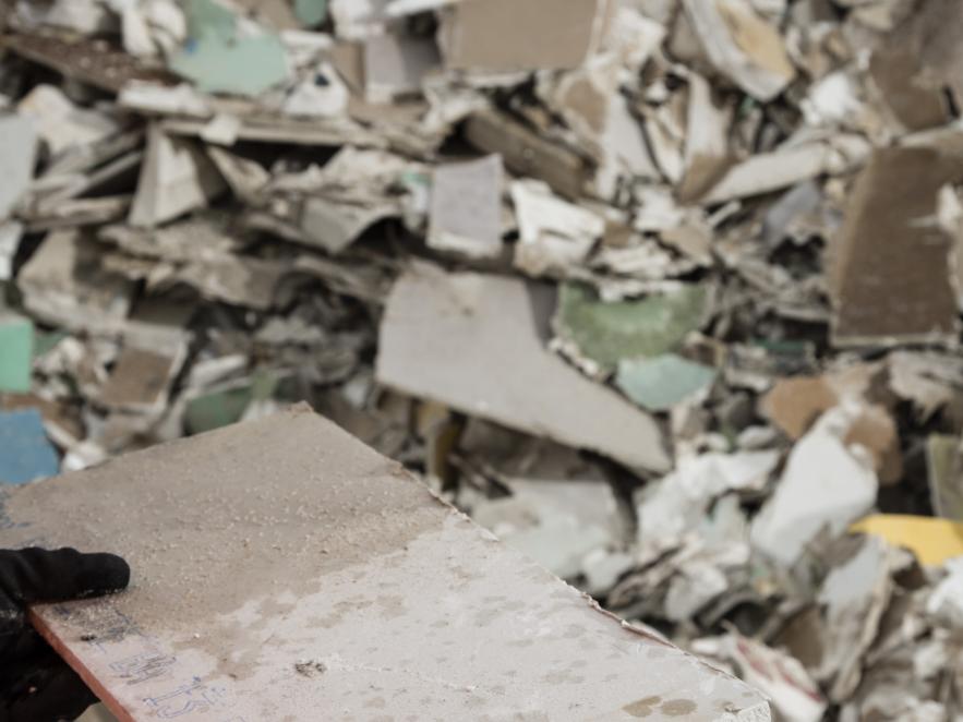 Person wearing gloves is holding a piece of broken gypsum ready for recycling