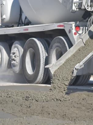 A man in a yellow safety vest is pouring concrete 
