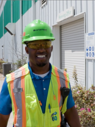 A man in yellow safety gear walks outside the manufacturing plant
