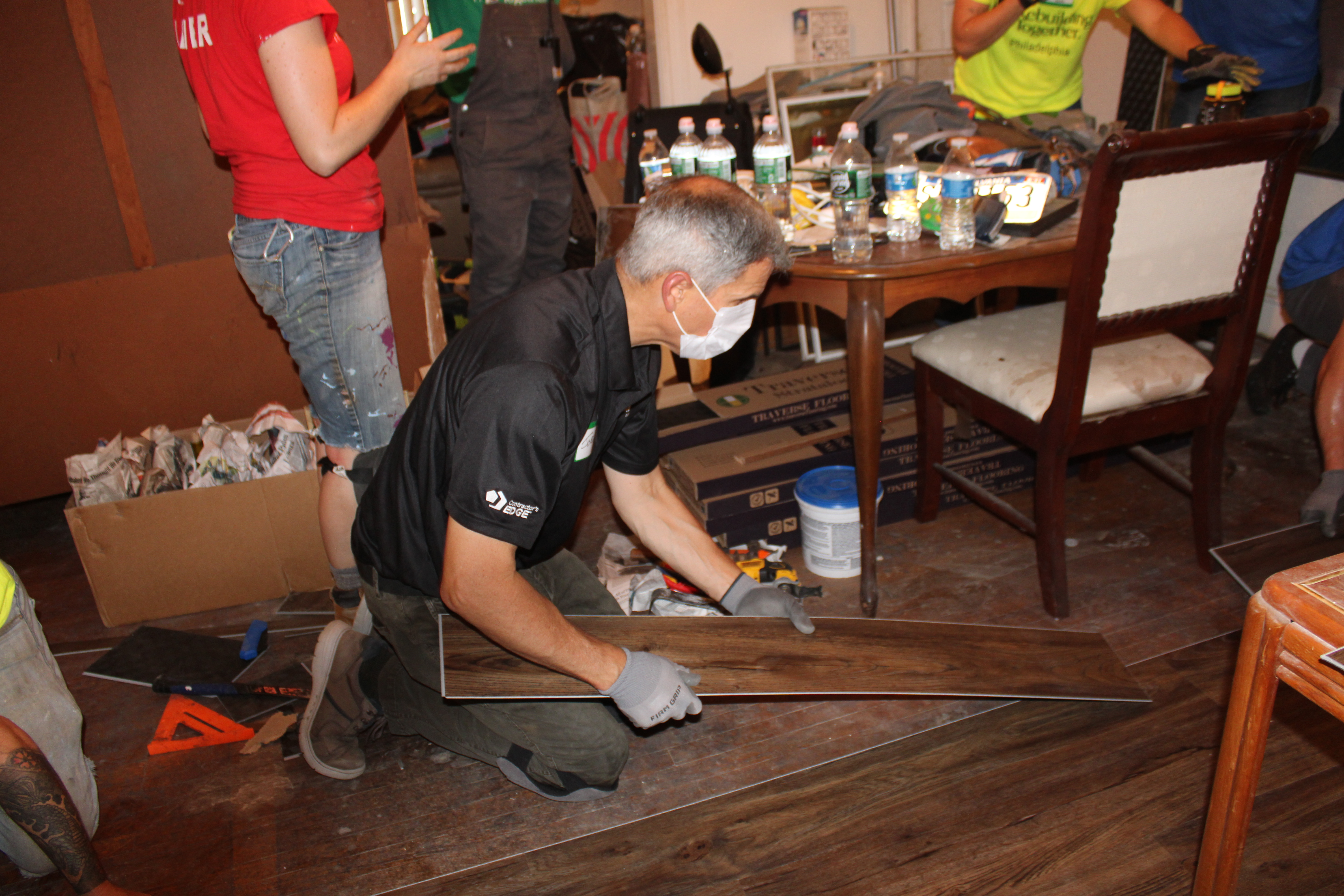 A man wearing a face mask installs flooring