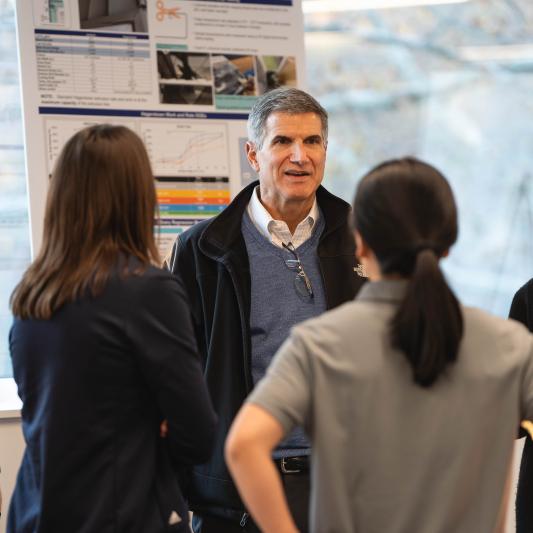 Group of five people gathered in front of a poster presentation display.