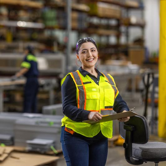Women wearing a safety vest stands on the warehouse floor