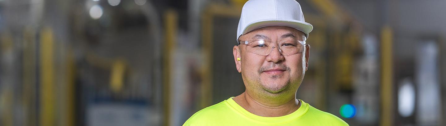 A male employee at a Saint-Gobain North America plant smiles, proud of his successful path in manufacturing and operations jobs.