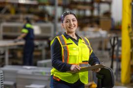 Women wearing a safety vest stands on the warehouse floor
