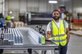 A male employee at a Saint-Gobain North America plant smiles, proud of his successful path in manufacturing and operations jobs.