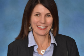 A woman with a blue suit smiles for the camera 