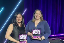 Two women, an Asian woman wearing a black dress and a white woman wearing a blue dress, hold Women MAKE Award trophies
