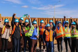 A group of people wearing safety vests and hard hats posting for a photo