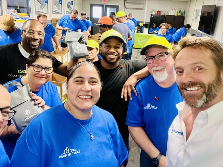 A selfie-style picture with a large group wearing blue company t-shirts at a volunteer event