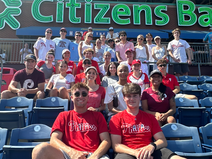 A group of young professionals wearing baseball t-shirts are attending a Philadelphia Phillies game