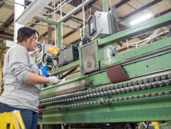 Woman using a large assembly line machine.
