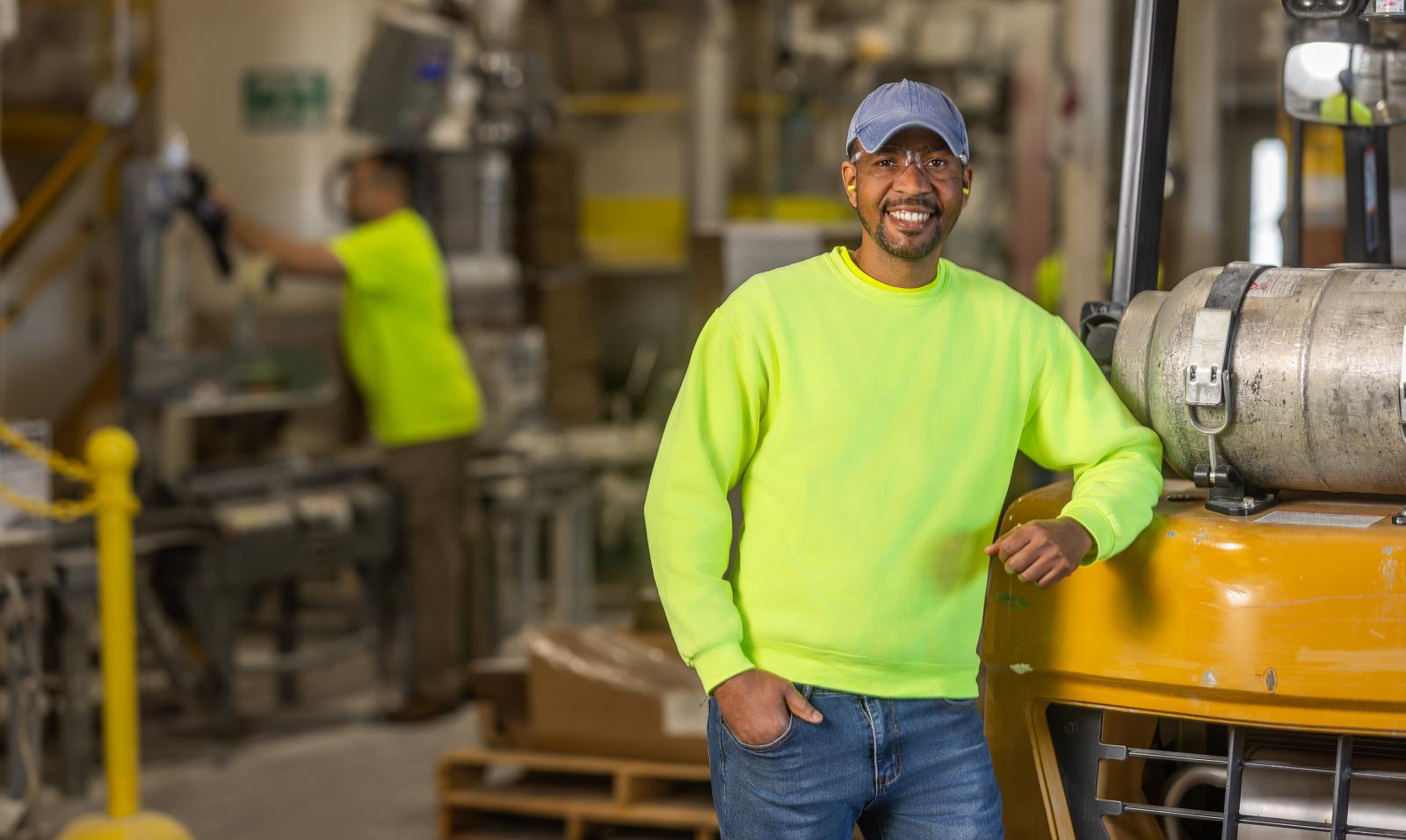 A male employee at a Saint-Gobain North America plant smiles, proud of his successful path in manufacturing and operations jobs.