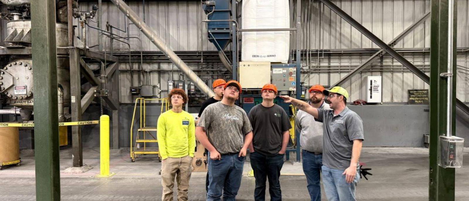 A group of trainees learning about good paying jobs with no experience in a modern manufacturing facility.