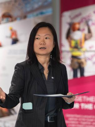 An Asian woman gives a presentation in front of a CertainTeed banner