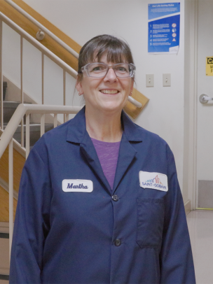 A woman wearing a Saint-Gobain blue safety suit stands in a stairwell. 