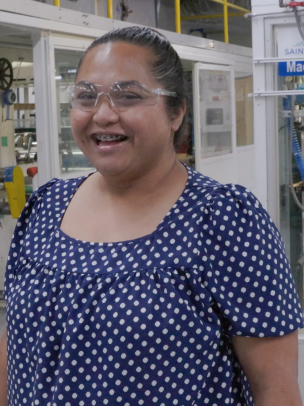 A Filipino woman wearing safety goggles stands on the manufacturing plant floor
