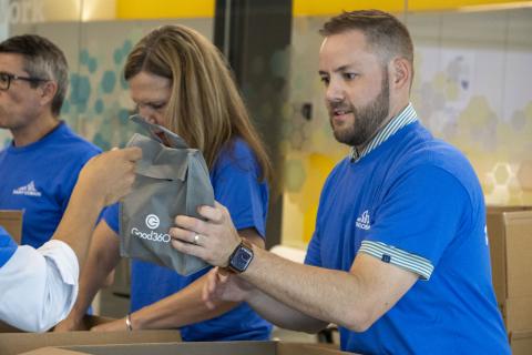 A man wearing a blue tshirt takes a Good360 bag to put into a box